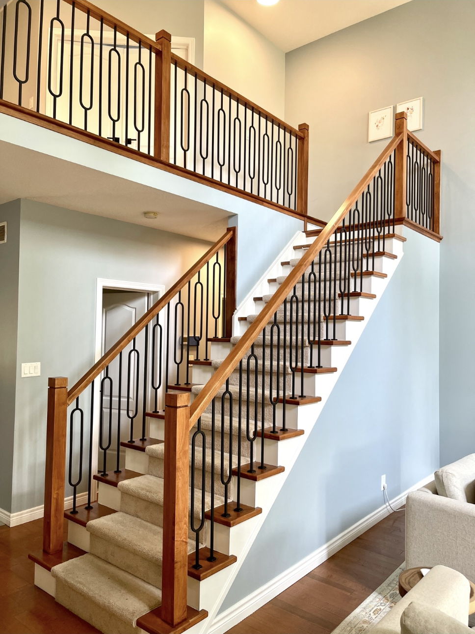 white and wooden staircase with wrought iron spindles and carpeting